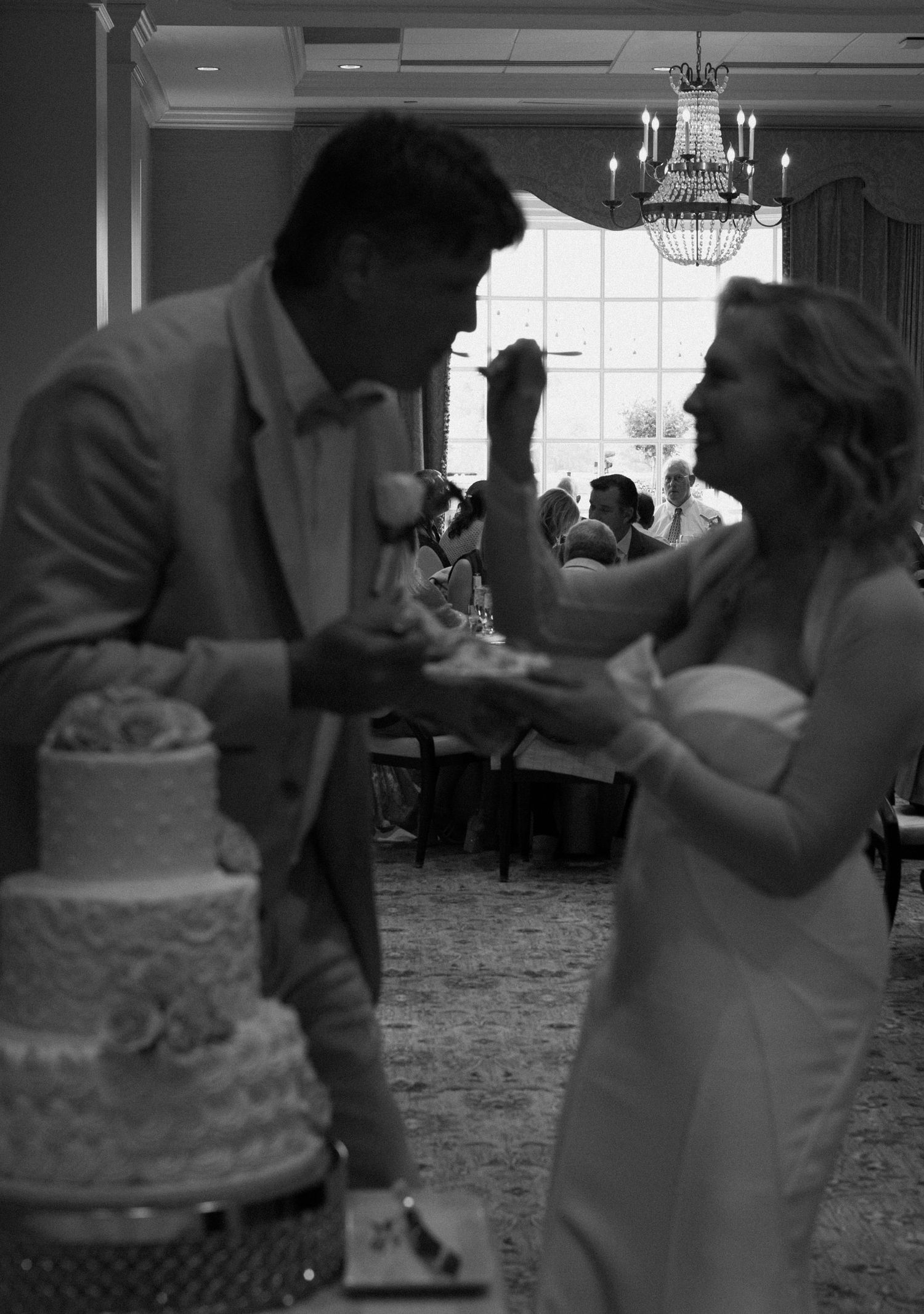A joyful moment at a wedding reception as a couple shares their first bite of wedding cake together.