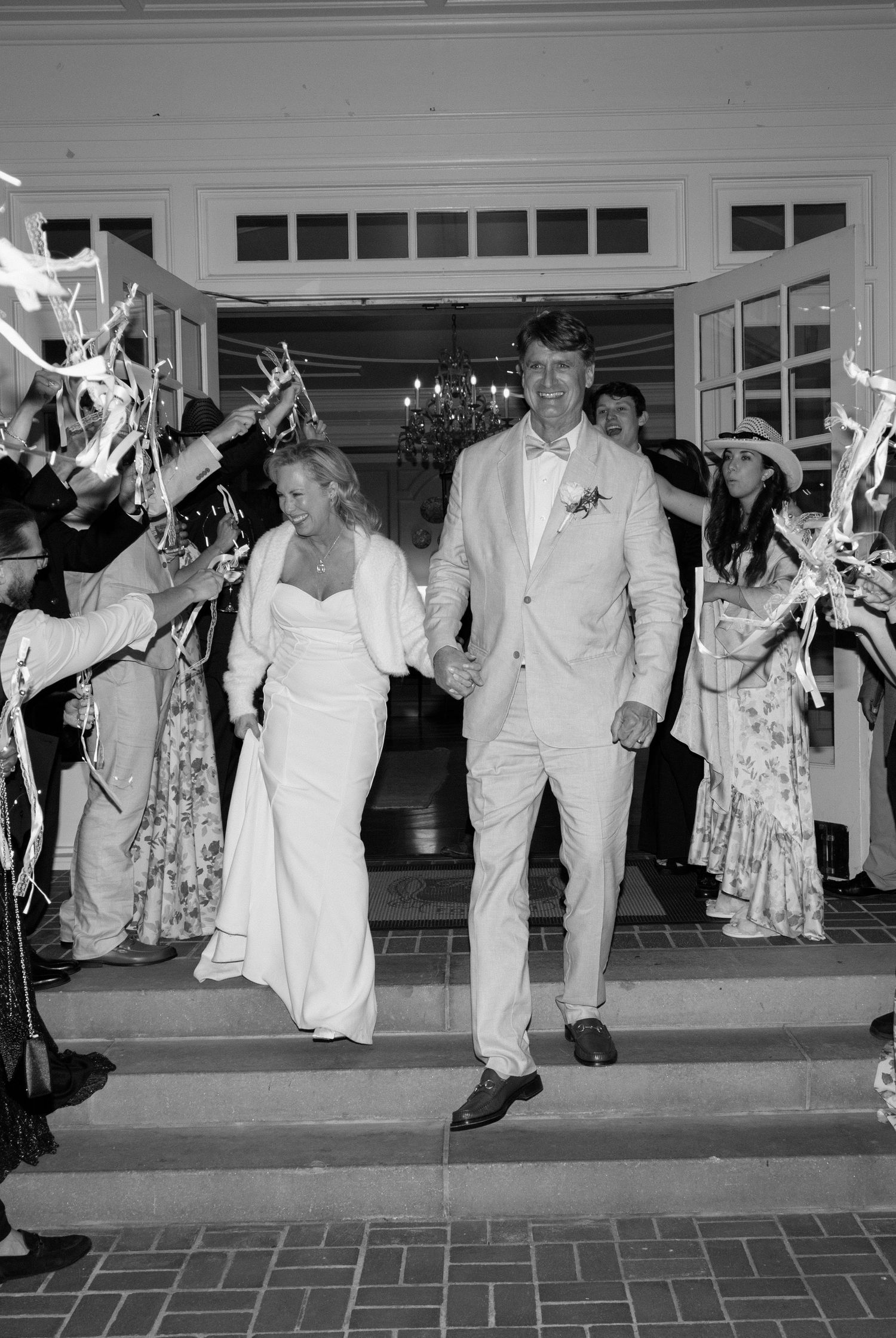 Wedding exit celebration with guests waving sparklers as couple walks through in formal attire at night.