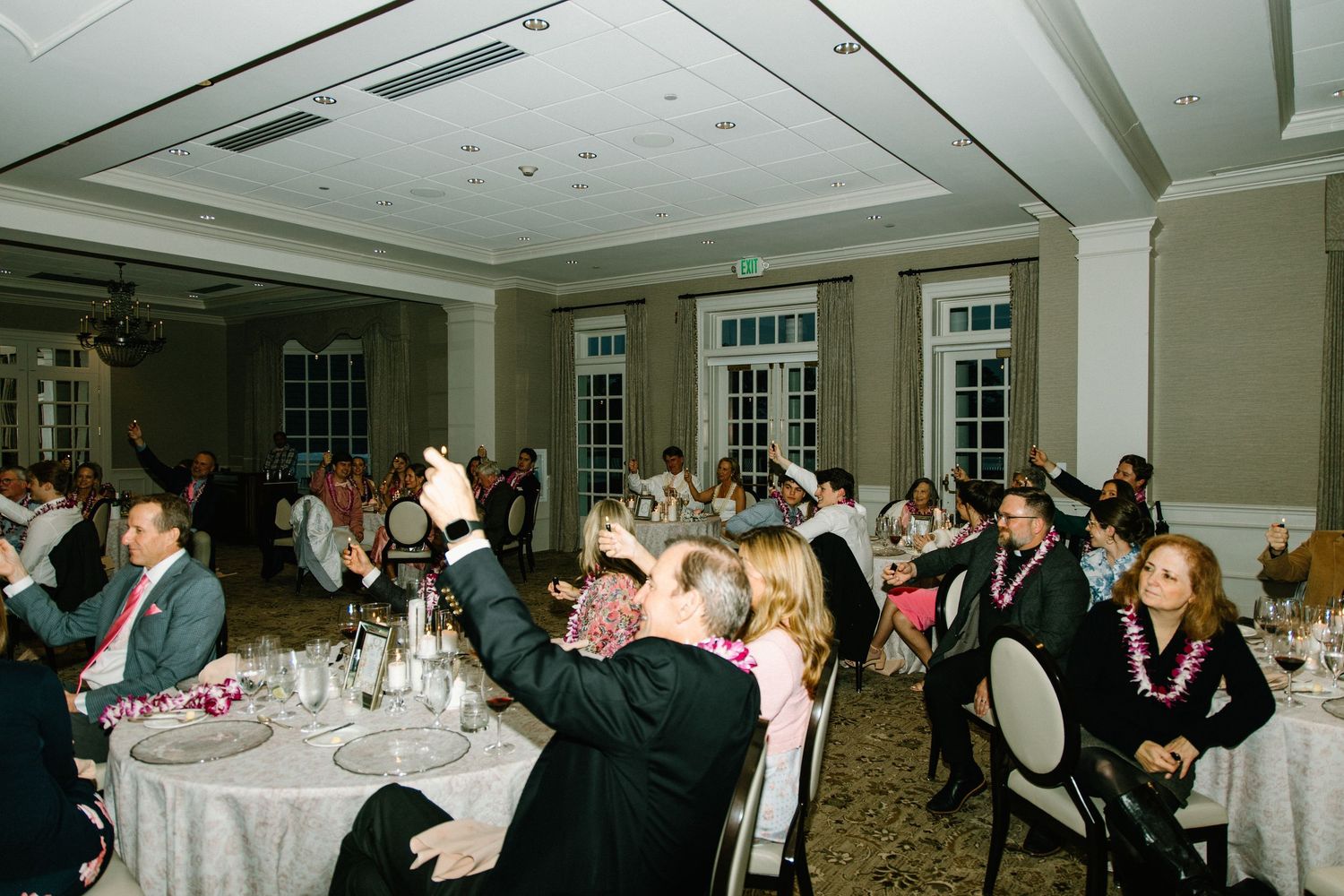 Group of guests mingling and dancing during an evening wedding reception in an elegant indoor venue.