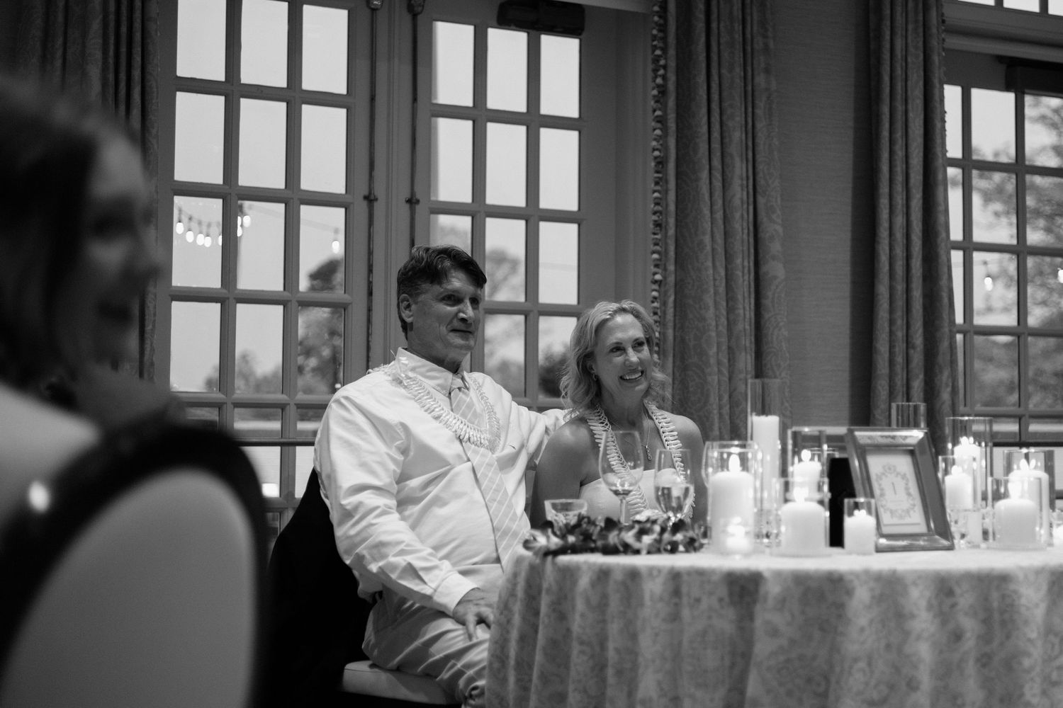 Historic photograph shows group seated around an interior table in black and white monochrome lighting.