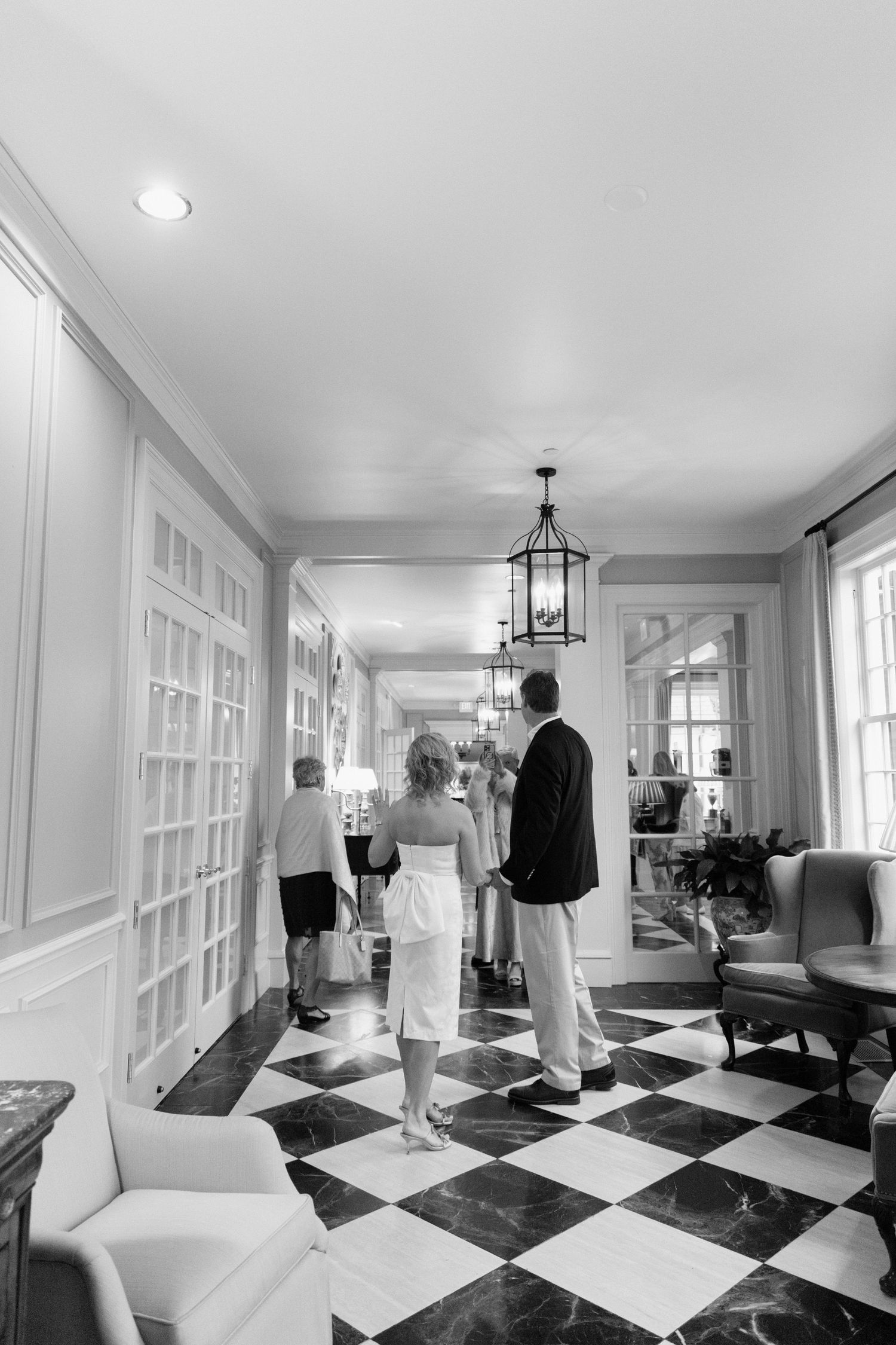 Four connected images show a long hallway with a striking black and white checkered marble floor and classic white interior.