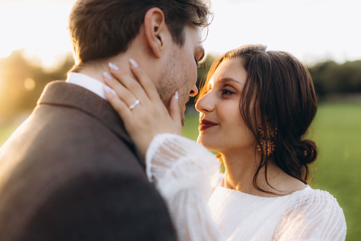 An intimate wedding portrait captured during golden hour in a sunlit field.