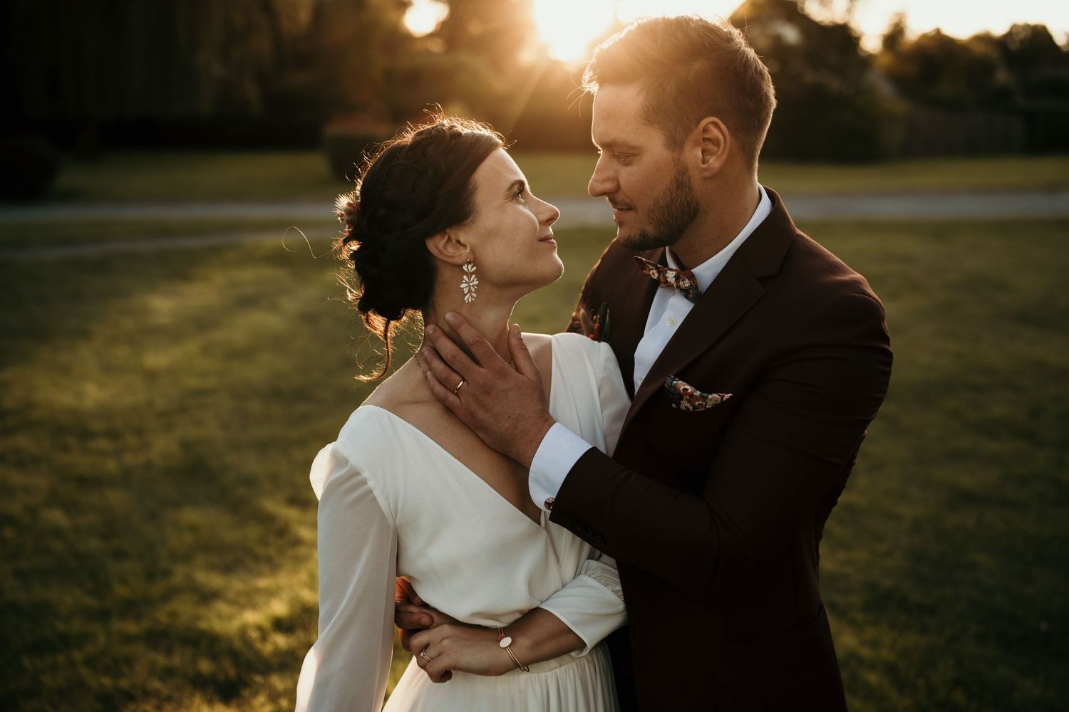 Romantic golden hour portrait of newlyweds in an elegant garden setting.