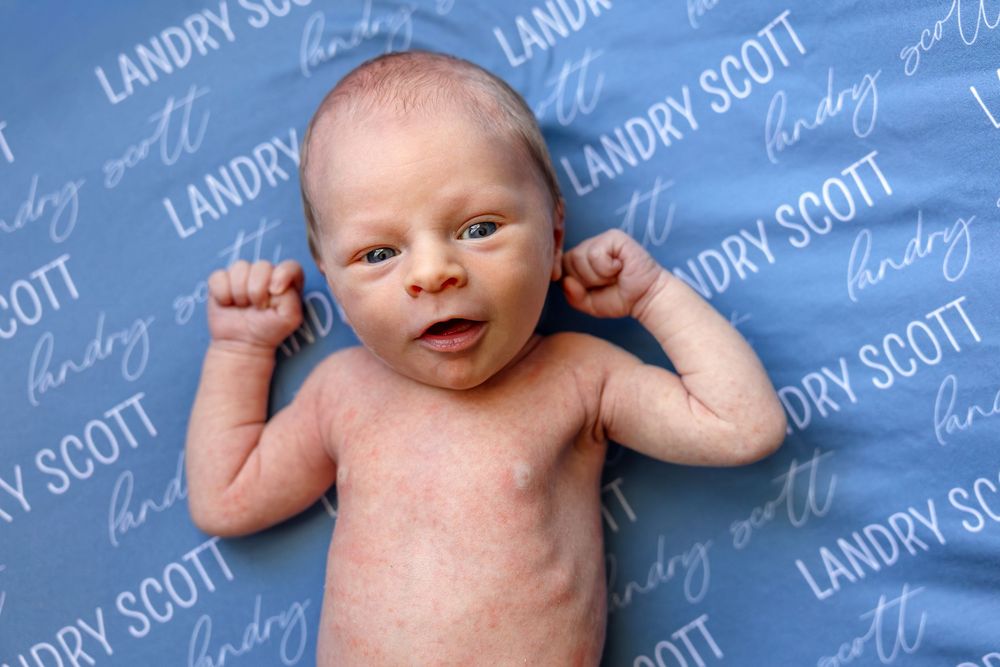 Newborn baby boy lying on a personalized blue blanket/