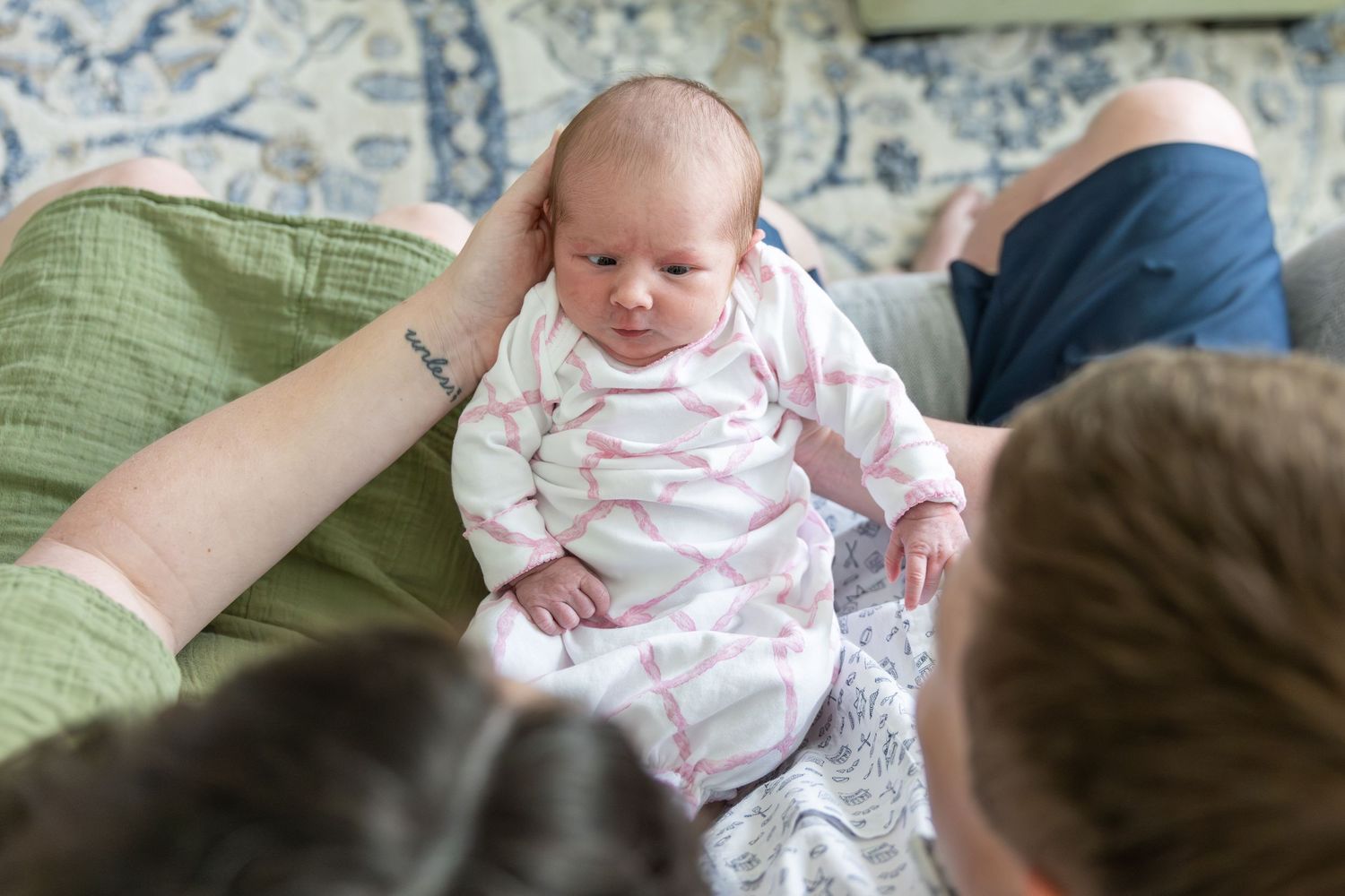 Mom & Dad cuddling a small baby in pink bow clothing by Jessie Peloso Photography.