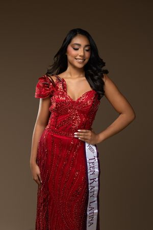 Young woman in red sequin gown wearing Teen Katy Latina pageant sash, posing elegantly against brown background.
