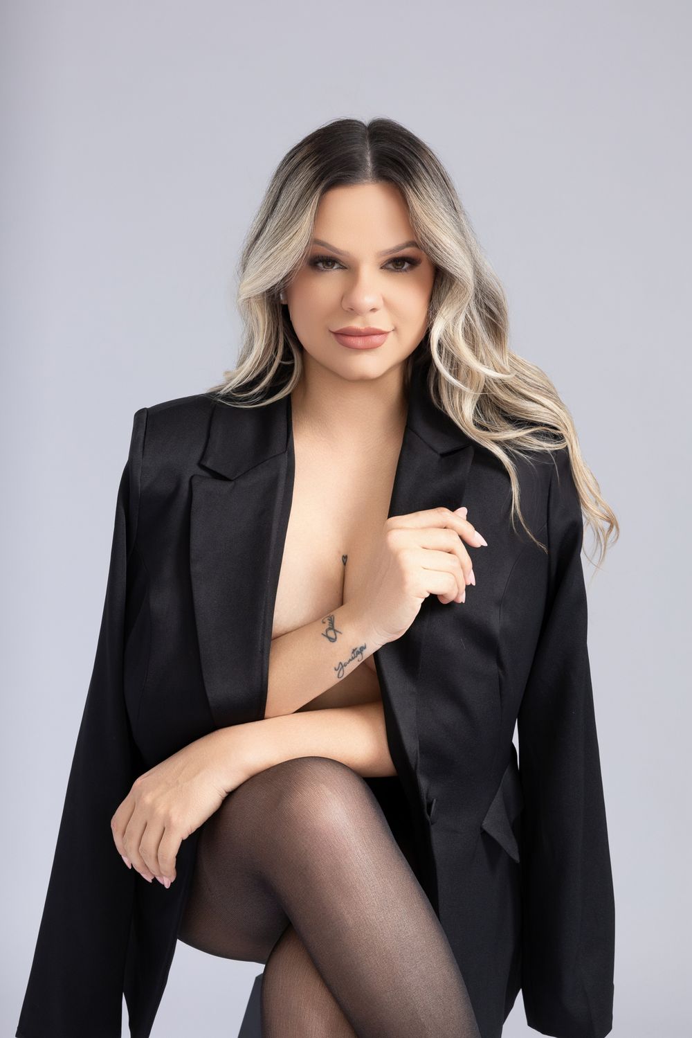 Professional fashion photo series featuring a black blazer and blonde hair against a gray studio backdrop.