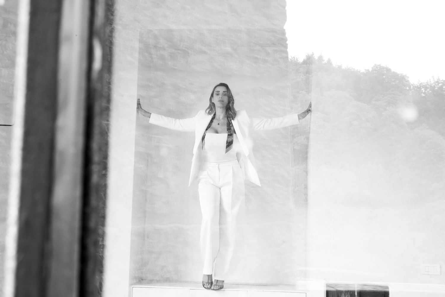 Artistic black and white shot captured through architectural framing in bright outdoor setting.