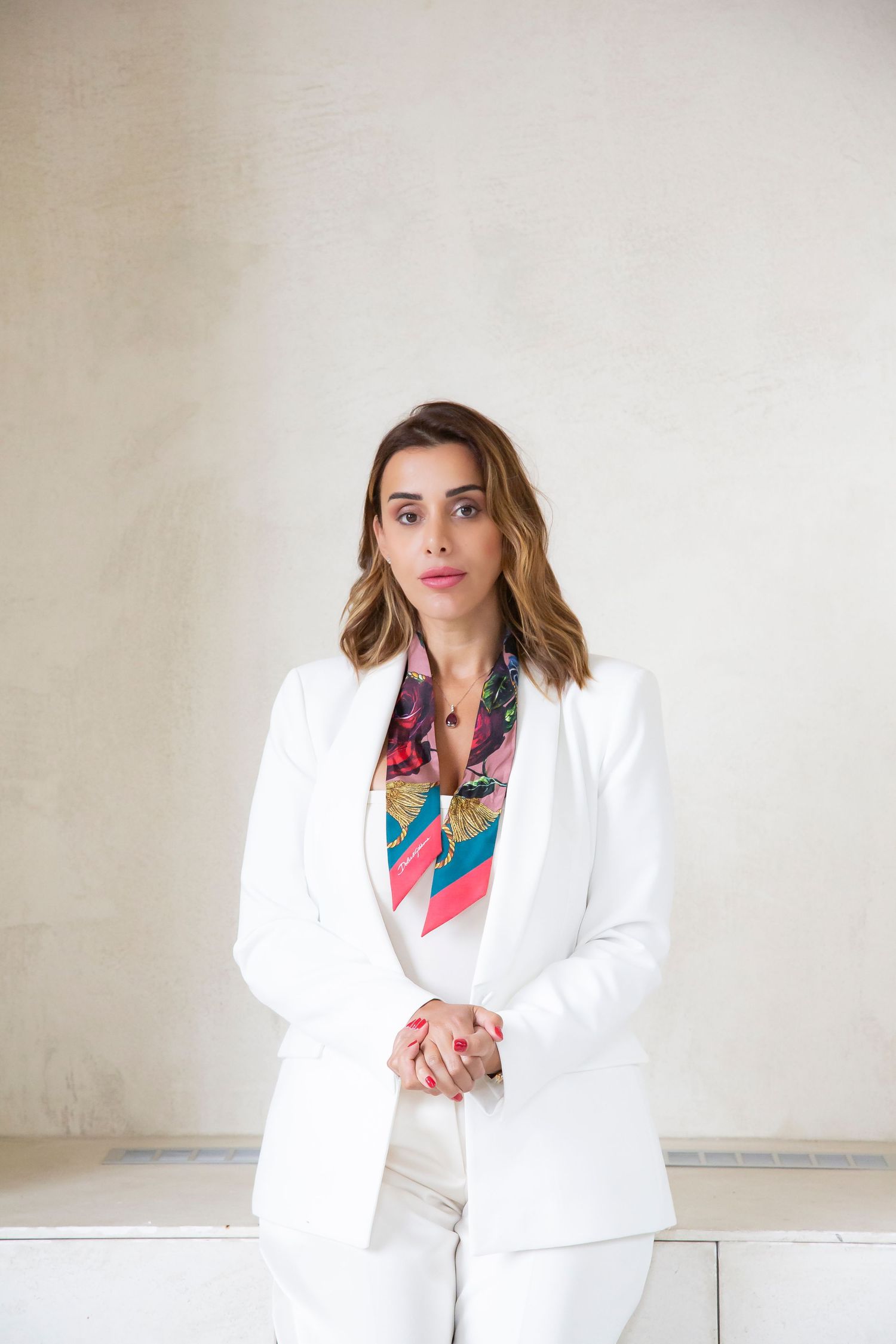 Professional portrait in crisp white suit accessorized with colorful patterned silk scarf.