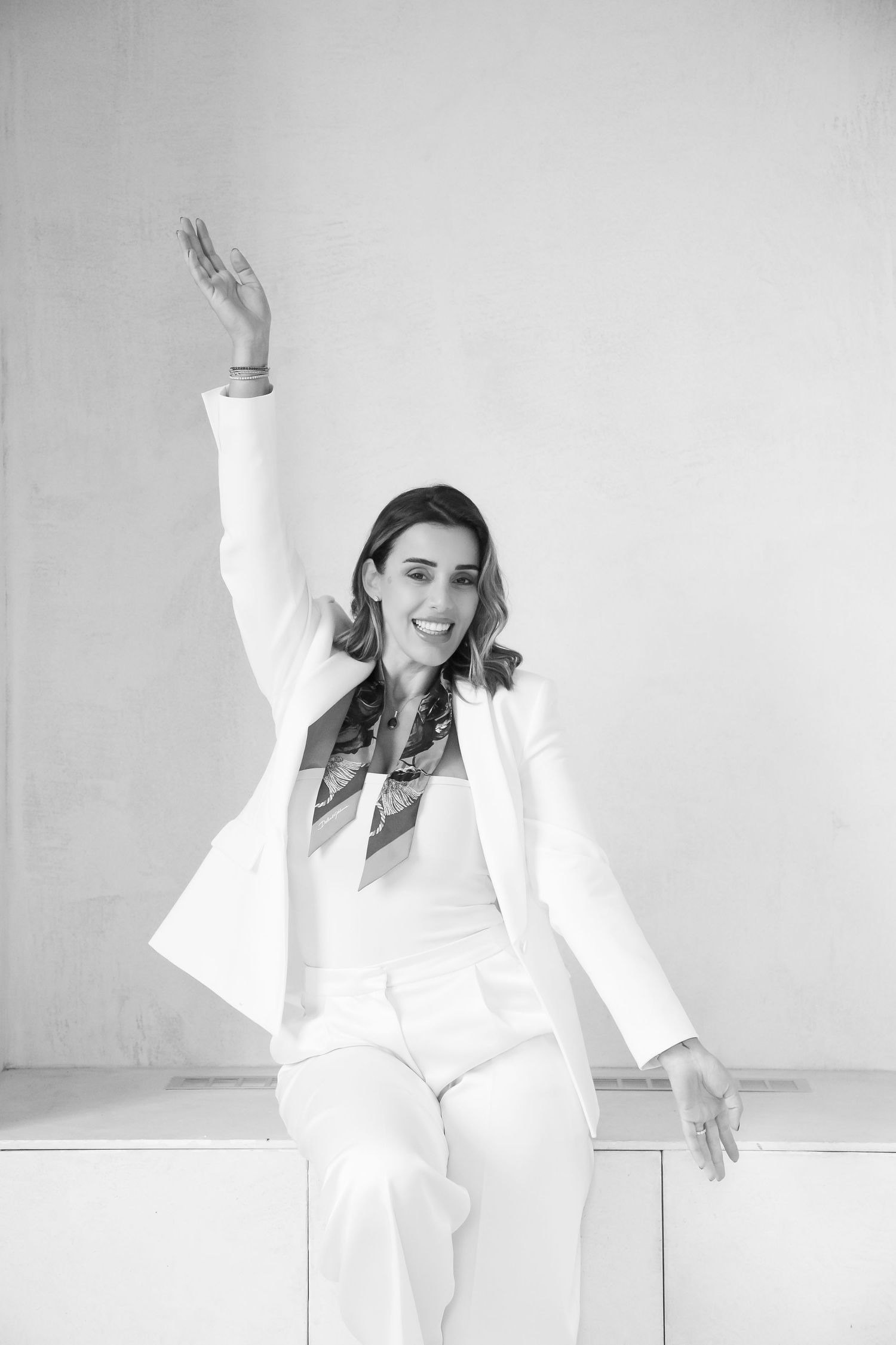 Energetic black and white portrait showing celebratory pose in white business attire.