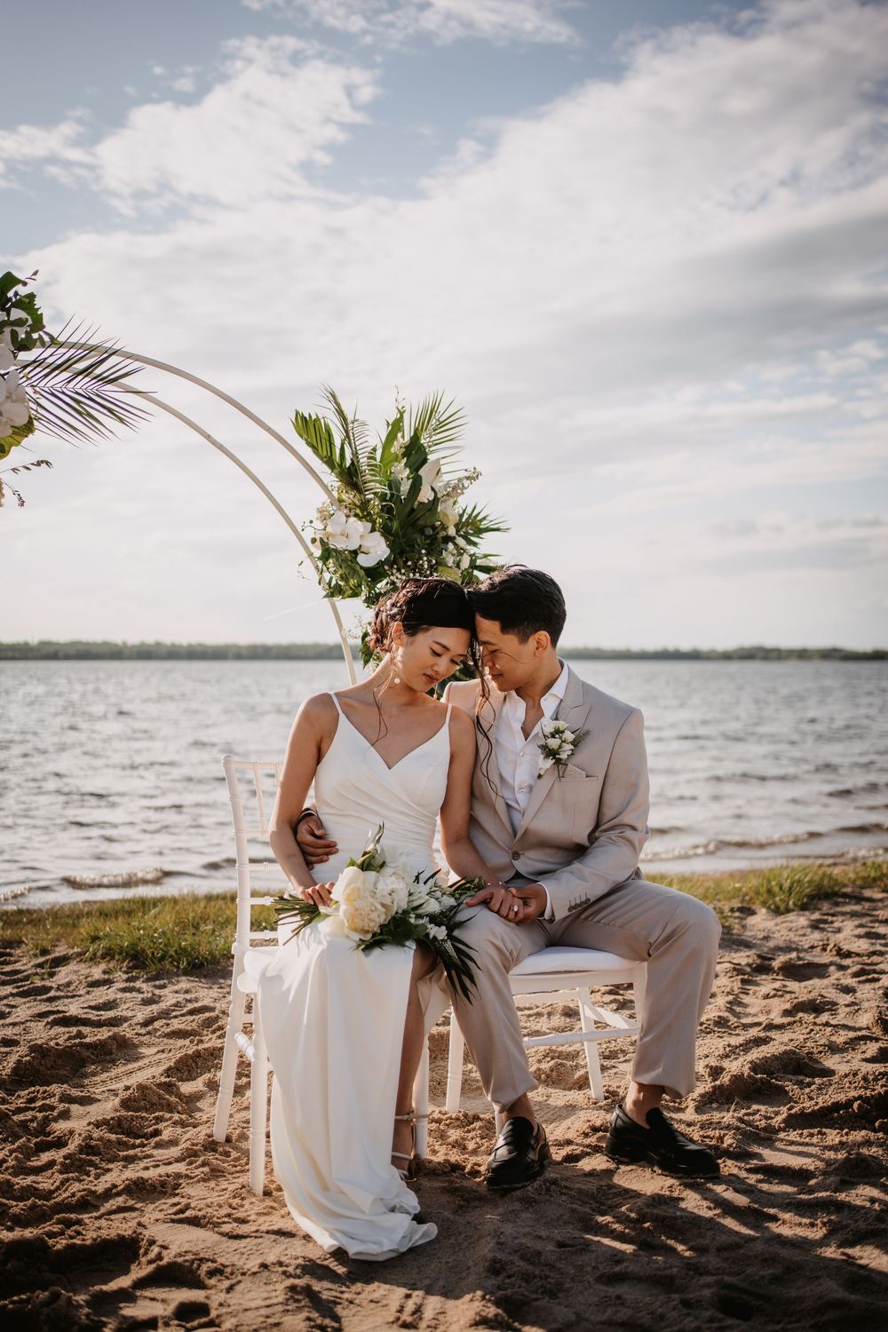 A romantic seaside elopement scene with a couple sitting on chairs at the beach during golden hour.
