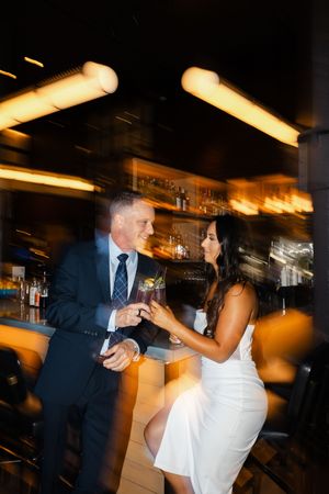 Couple enjoys drinks at an upscale bar with motion blur lighting effects and warm ambiance.