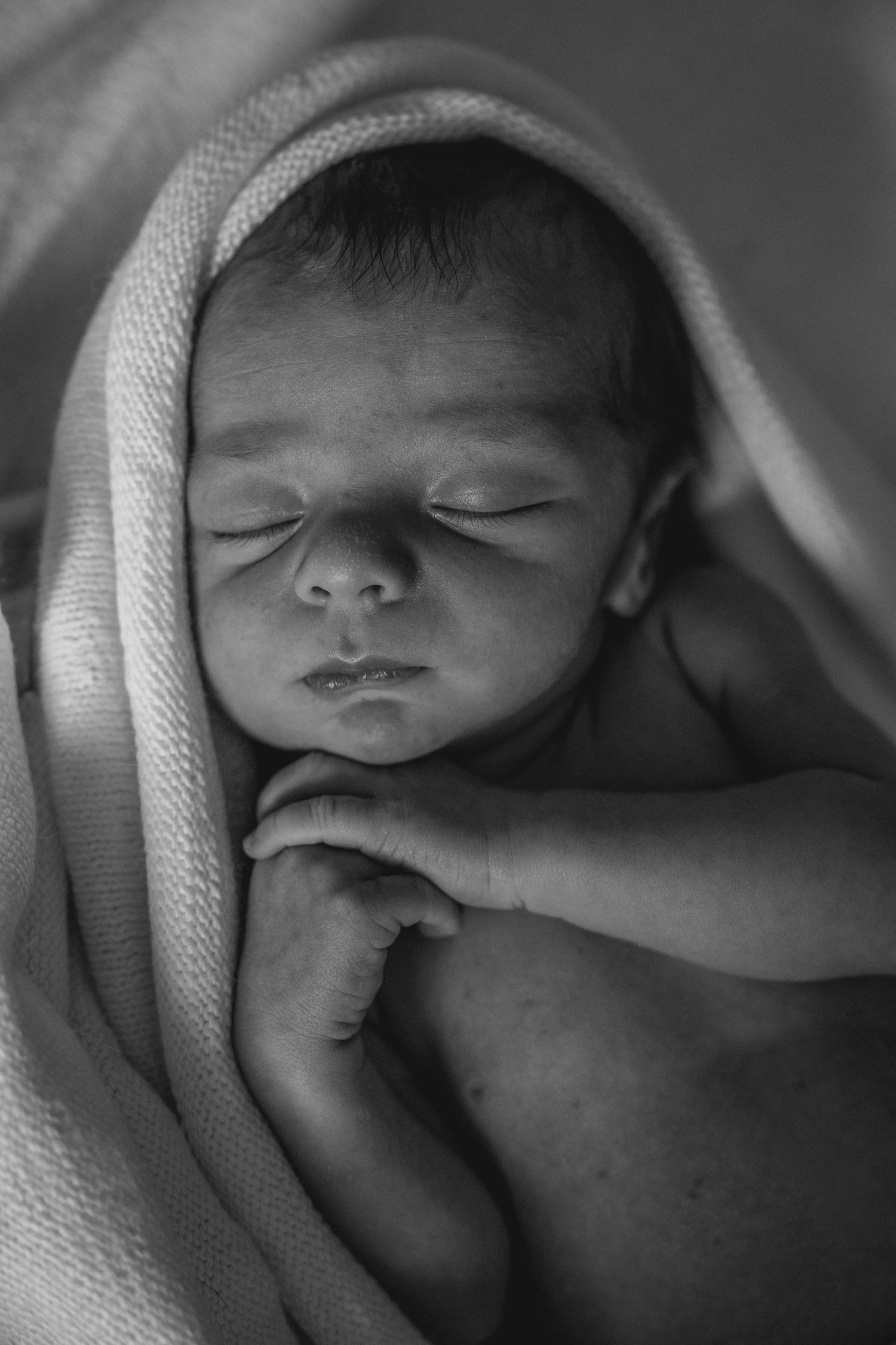 Six black and white photos of a sleeping newborn baby wrapped in white cloth, displayed in a horizontal layout.