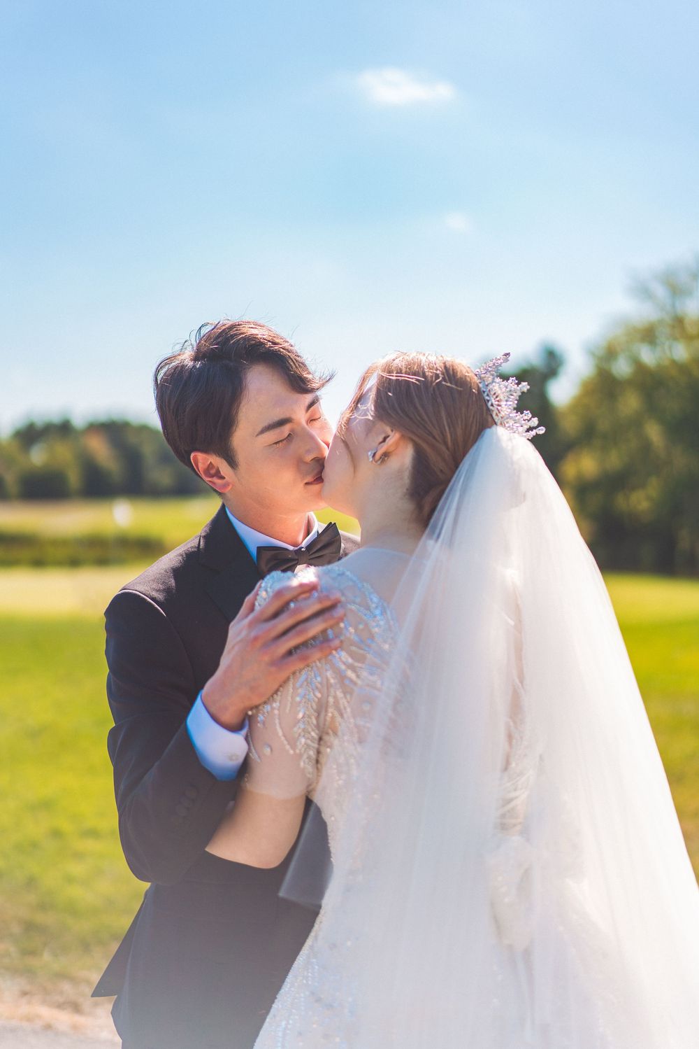 A romantic wedding couple sharing a kiss outdoors on their special day.
