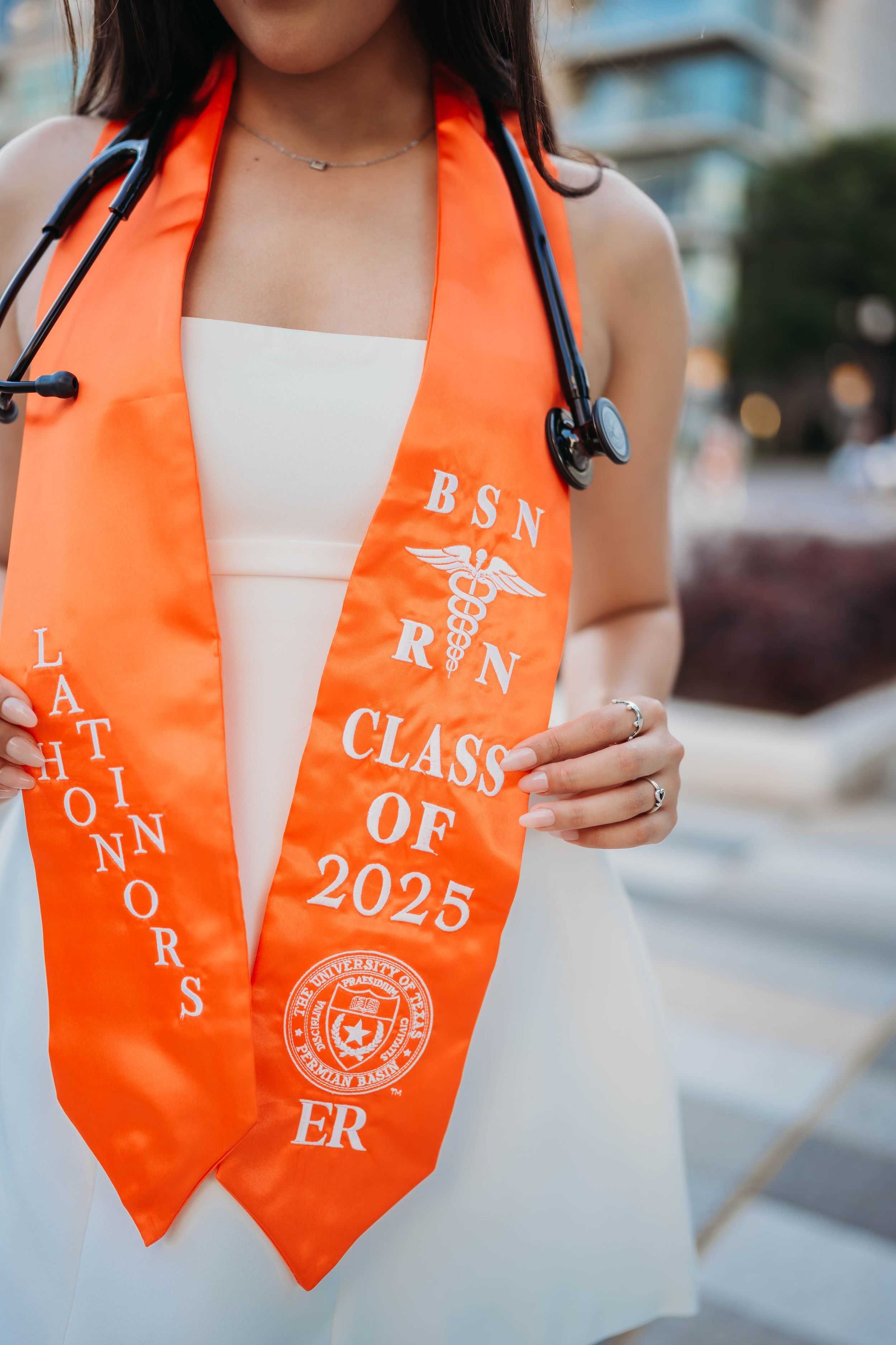 Close-up shots of a bright orange graduation stole with Class of 2025 text and embroidered details displayed on white fabric.