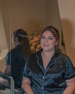 Person wearing black satin pajamas sitting indoors with decorative lighting.