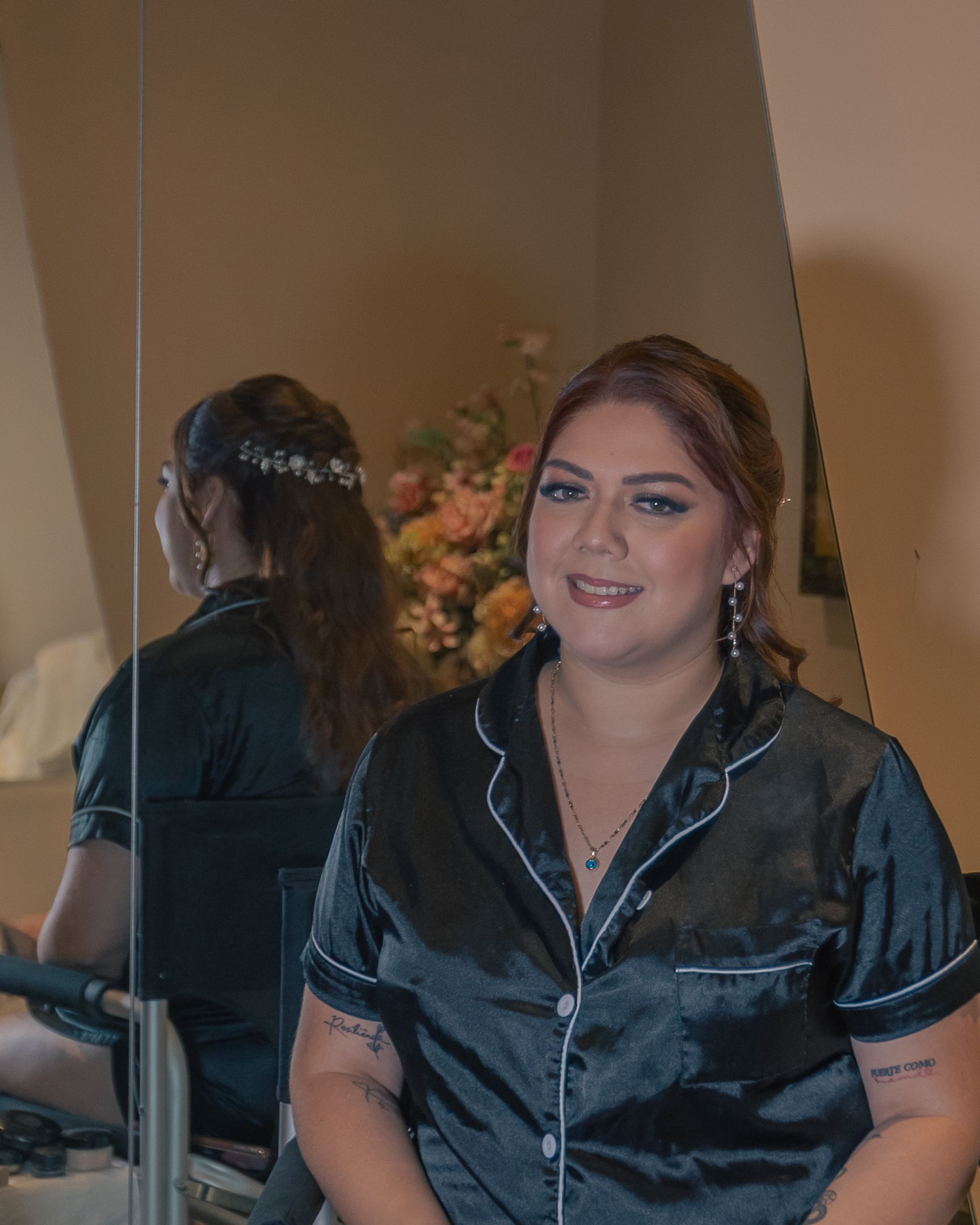 Person wearing black satin pajamas sitting indoors with decorative lighting.