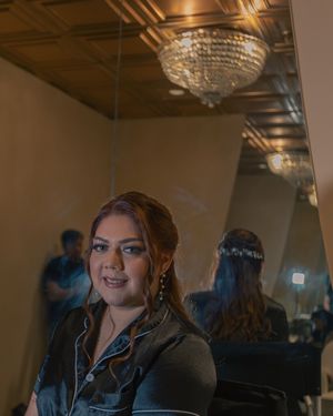 Interior shots of person in dark pajamas with glamorous makeup under warm lighting.