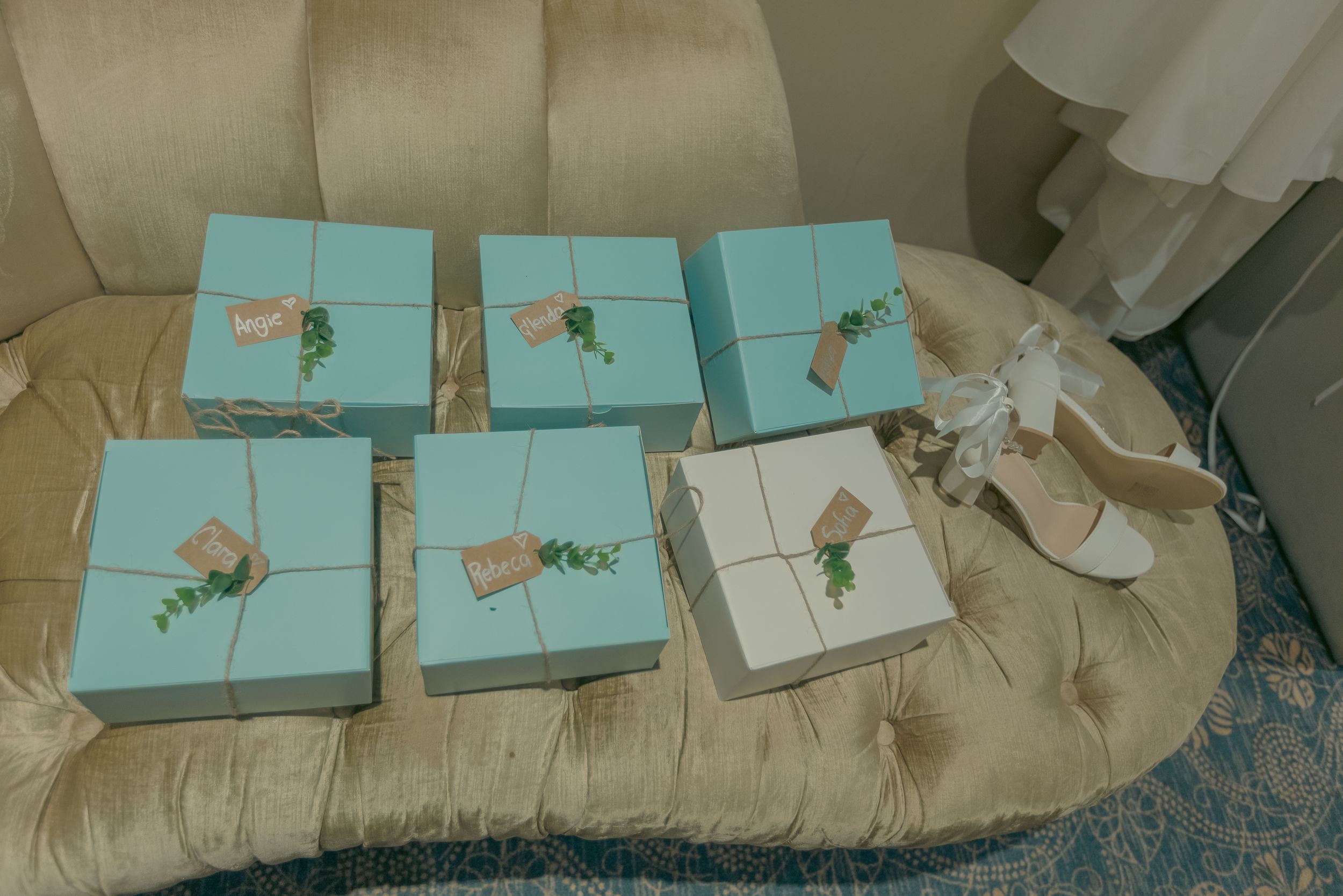 Row of turquoise gift boxes arranged on cream-colored surface.
