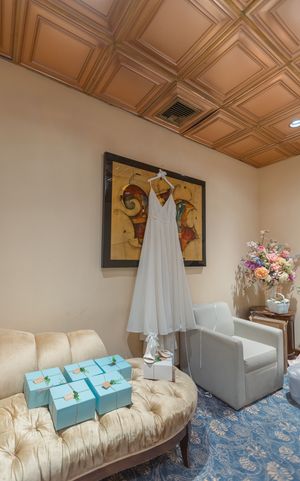 Wedding dress and turquoise boxes arranged in room with wooden ceiling.