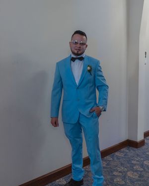 A person wearing a bright blue suit poses in a hotel hallway.