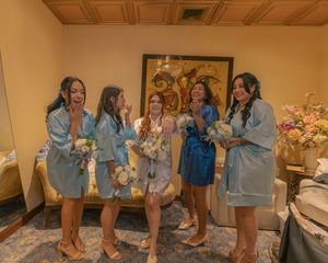 Bridesmaids in matching outfits sharing a fun moment during wedding preparations.