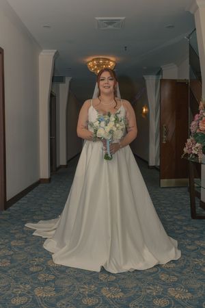 Bride in flowing white gown posing on patterned hotel carpet.