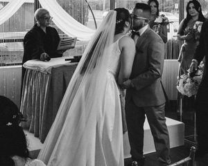 A black and white photo of a wedding ceremony with the couple at the altar under white draping.