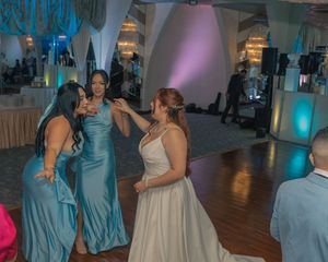 Wedding guests in formal attire dancing and celebrating on a wooden dance floor.