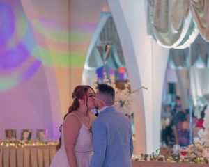 A romantic moment during a wedding reception with purple and green lighting effects.