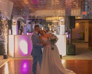 A couple sharing their first dance at a wedding reception with dramatic lighting effects.
