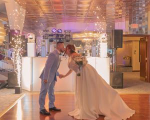 Wedding couple dances under sparkling lights in an elegant ballroom during their first dance.
