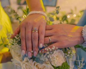 Wedding rings displayed with delicate white roses and greenery in soft lighting.