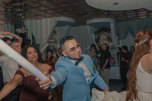 Wedding guests dancing and celebrating on a dimly lit dance floor.