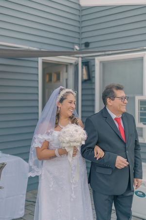A couple shares a romantic moment during their wedding photoshoot against a blue-sided building.