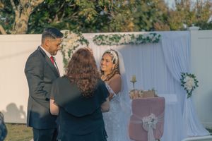 Wedding photoshoot in an outdoor garden setting with white decor and natural lighting.