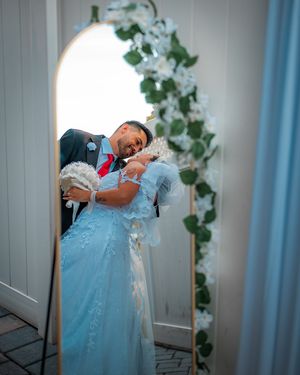 Wedding couple shares intimate moment against blue interior backdrop.