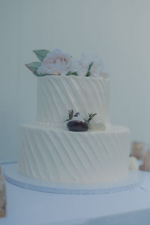 An elegant white wedding cake with diagonal textured tiers decorated with delicate flowers.