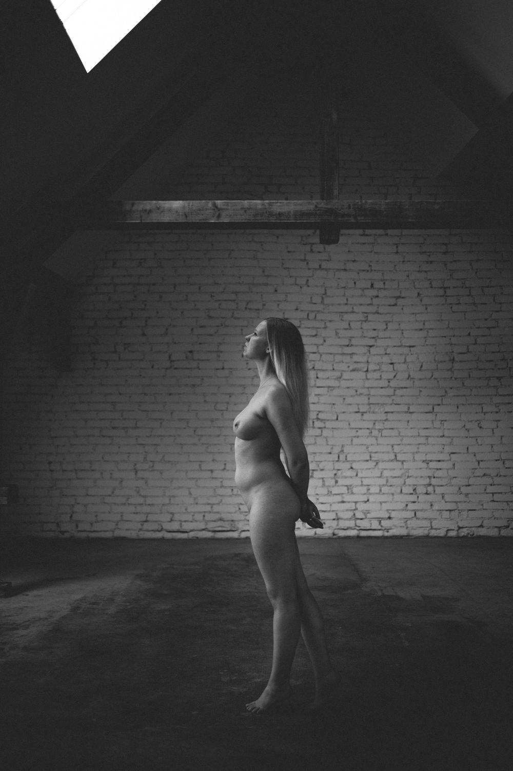 A dramatic black and white dance sequence shows a figure in white moving against a dark brick wall backdrop.