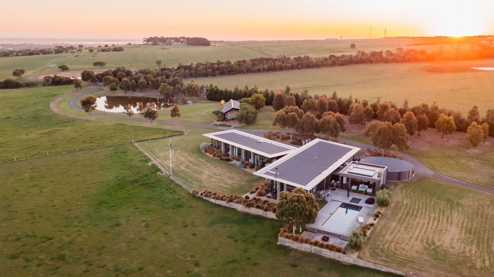 Drone shot of luxury homes and buildings spread across rolling countryside at sunset.