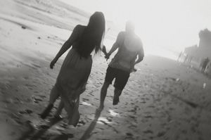 Silhouetted figures walking and playing together on a misty beach in black and white.