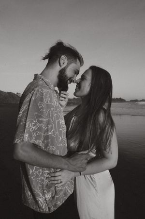Black and white photo series of a couple in an intimate embrace on a beach with dramatic lighting.