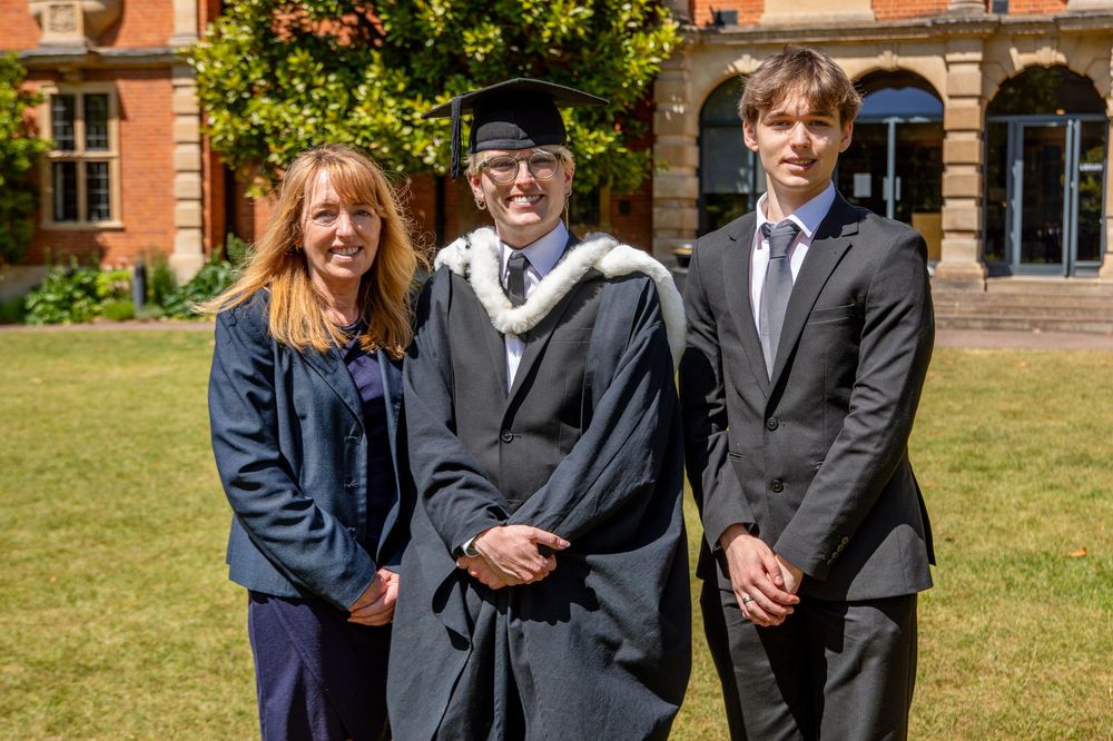 Graduates pose for photos outside historic university building on graduation day.
