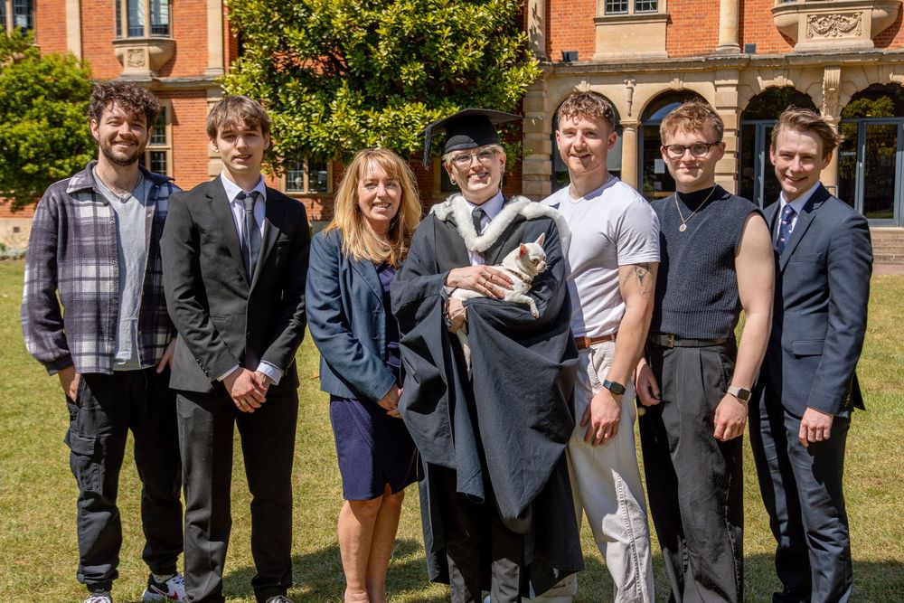 Graduates gather for group photos outside historic red brick university building.