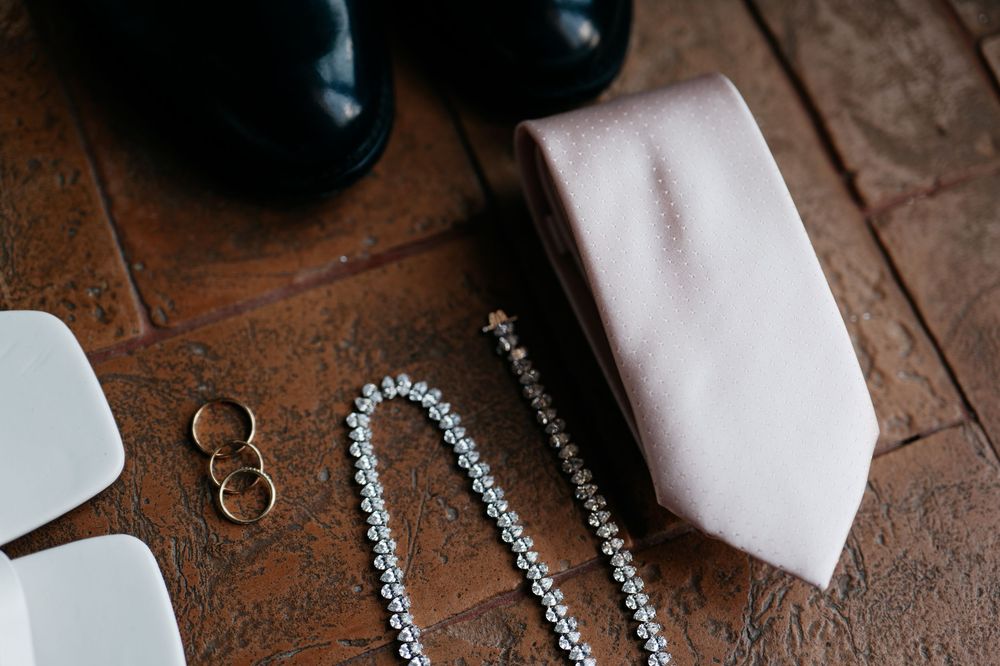 Wedding rings and bridal accessories arranged on a rustic wooden surface with delicate details in natural light.