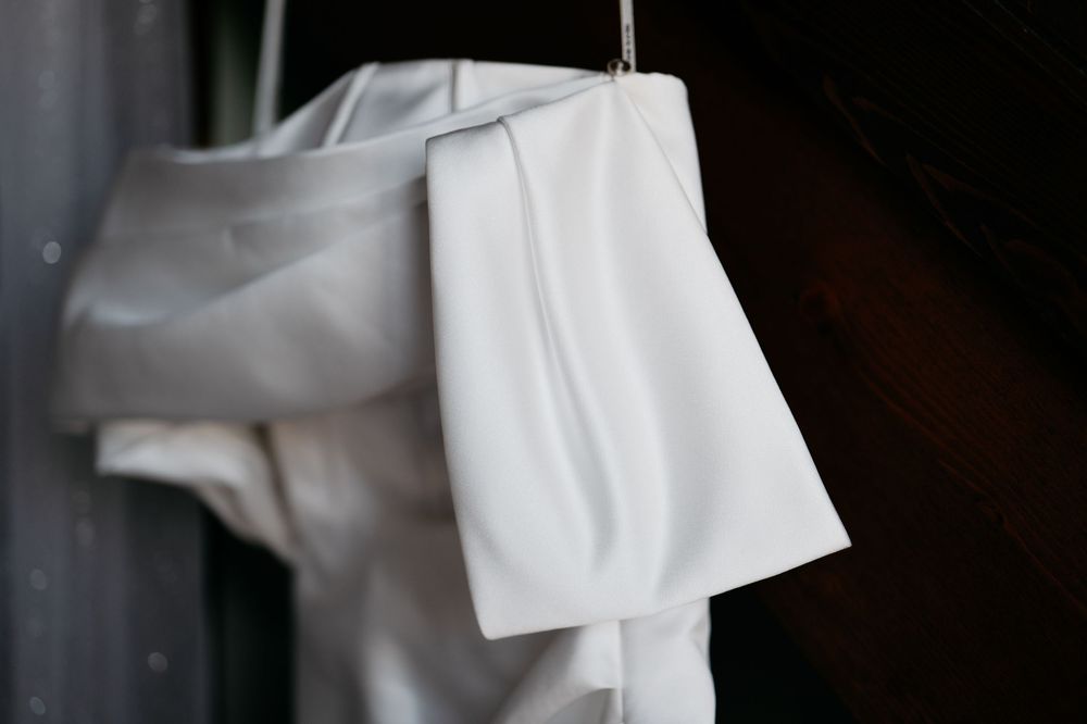 White wedding dress fabric detail hanging with soft natural light and shadows.
