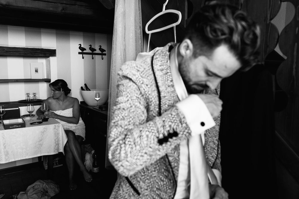 A person in a patterned sweater holds a garment in a dressing room.