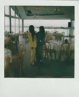 Vintage Polaroid photo of two people in a waterfront dining room with star decorations on the ceiling.