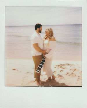 A couple shares an intimate moment on a serene beach during sunset, with soft pastel tones in a vintage Polaroid style.