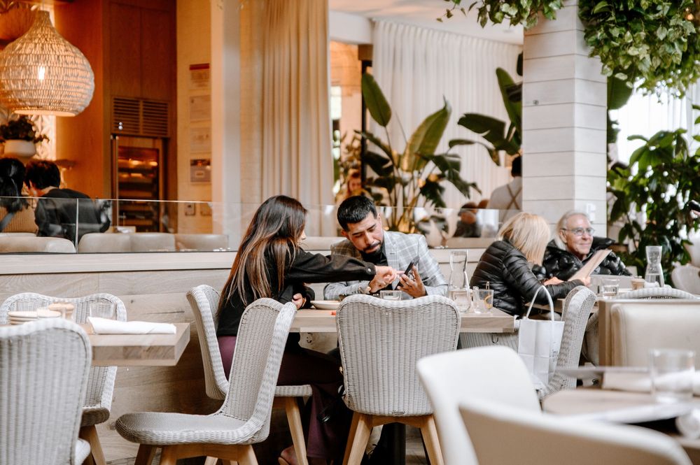 Bright modern restaurant dining area with comfortable upholstered seating and warm lighting.